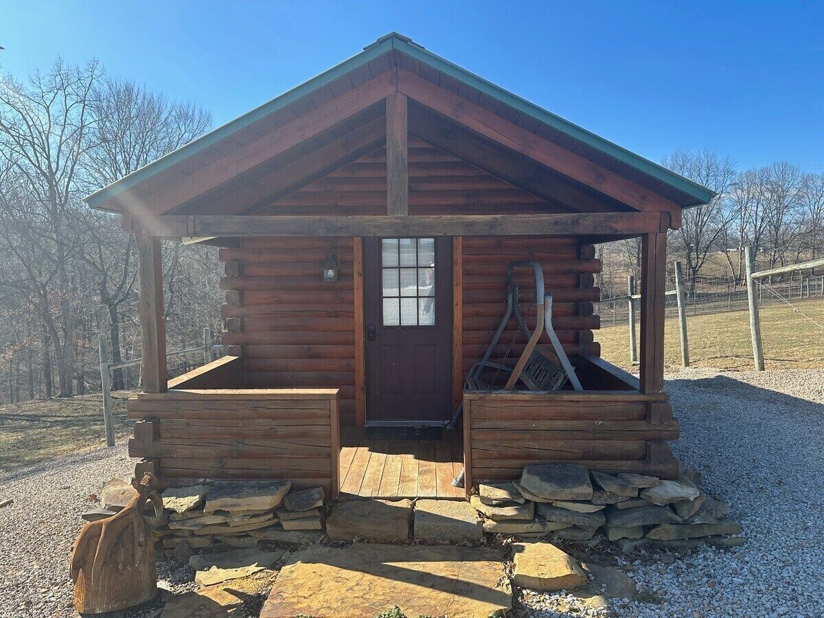 A small wooden cabin with a pitched roof, a front door, and a porch area.