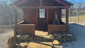 Una pequeña cabaña de madera con techo inclinado, una puerta principal y un porche.