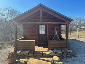 A small wooden cabin with a pitched roof, a front door, and a porch area.