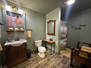 A bathroom with a wooden vanity, a toilet, a mirror, and a shower curtain.