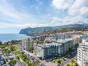 A coastal cityscape with modern buildings, a curved road, and a view of the sea.