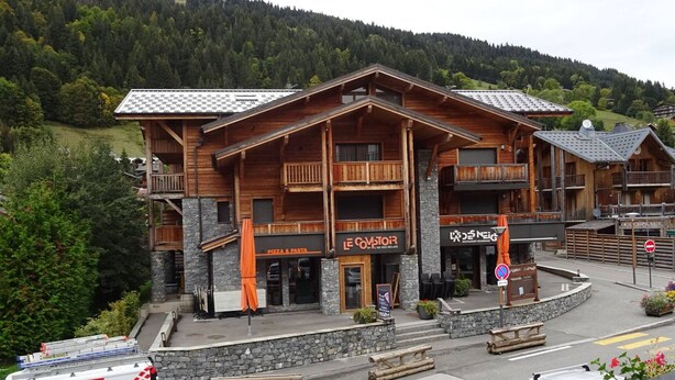 A wooden building with balconies, a pizza and pasta restaurant, and a sign for 'Le Comtoir'.