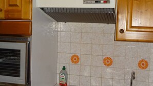 A kitchen with a stove, sink, and a cabinet above the stove. - Central Studio for 2 in Les Gets - Balcony, Free WiFi, Linens Included (Les Gets)