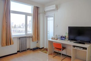 A hotel room with a large window, a desk with a television, and a radiator. - Beijing Zhonggong Hotel (Beijing)