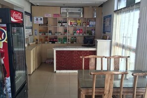 Interior de restaurante con mostrador, zona de asientos y unidad de refrigeración.