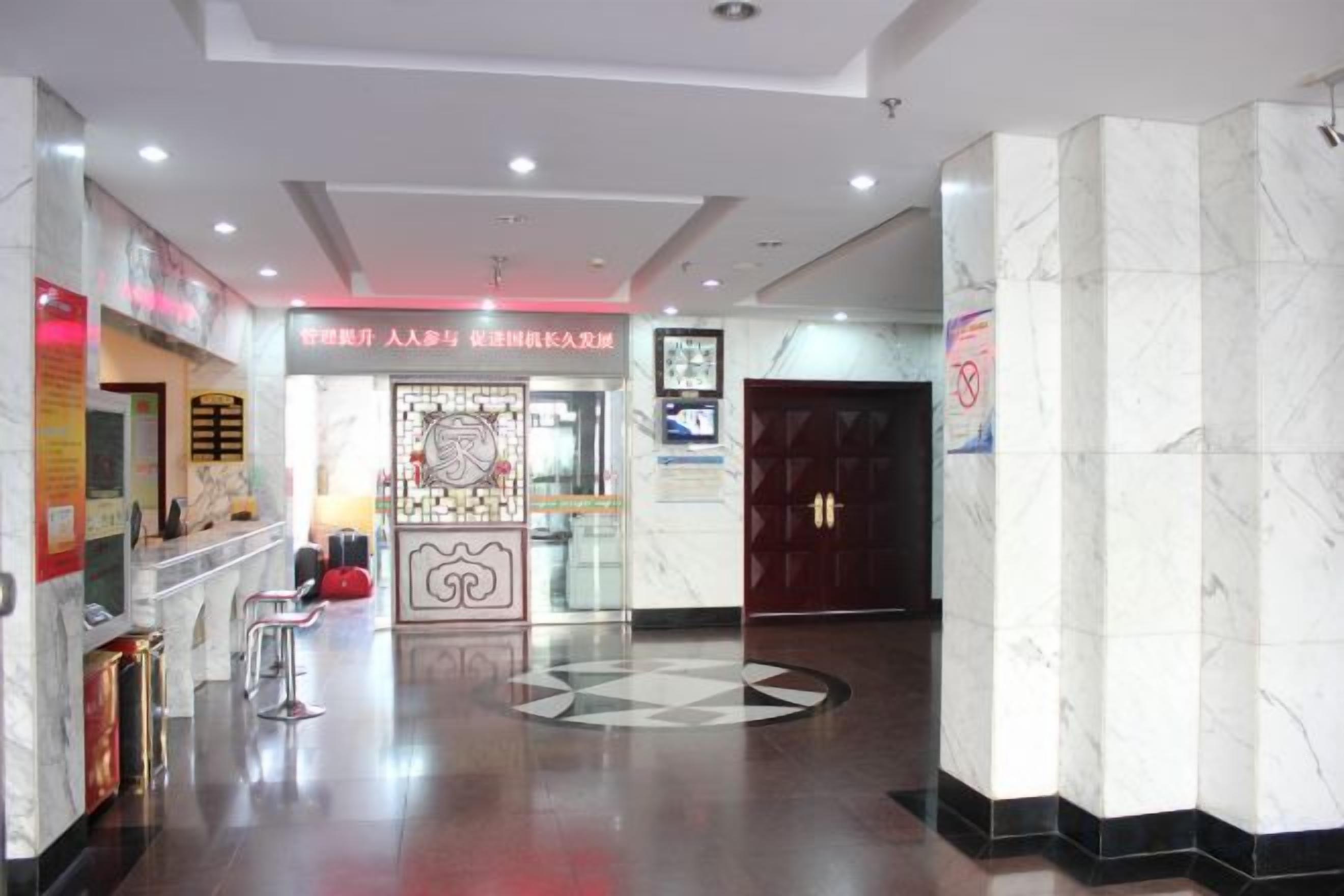 A hotel lobby with a reception desk, seating area, and a decorative wall.