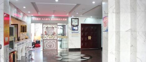 A hotel lobby with a reception desk, seating area, and a decorative wall.