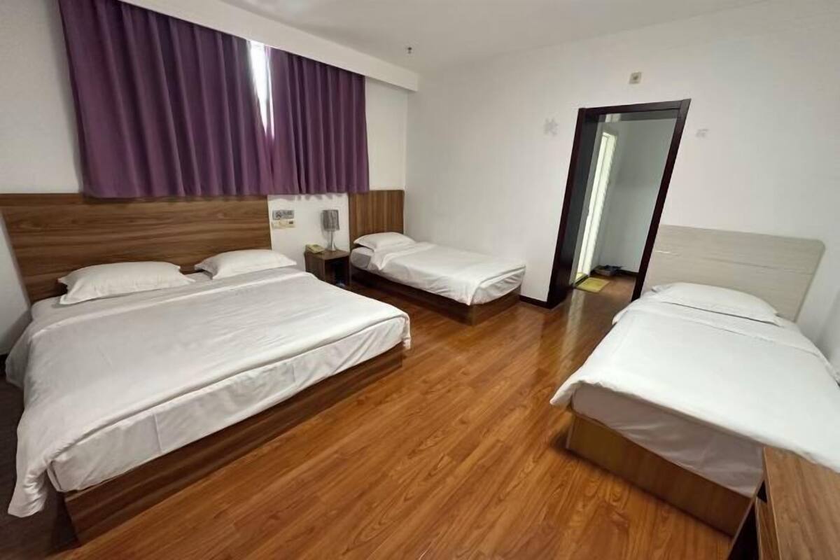 Ein Hotelzimmer mit zwei Betten, Holzboden, einem Spiegel und einer Tür.