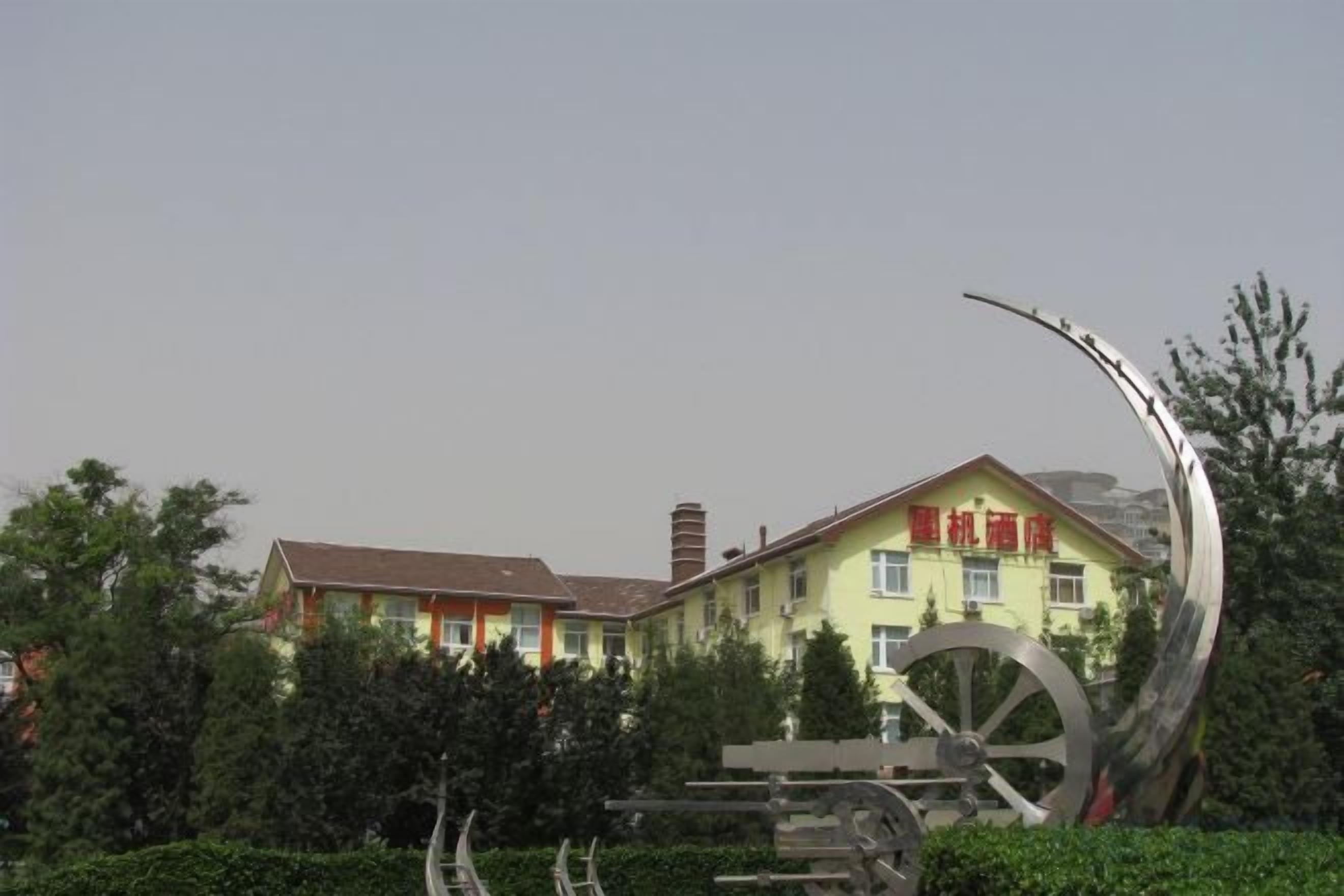 Ein Gebäude mit einer großen, metallischen Skulptur davor.