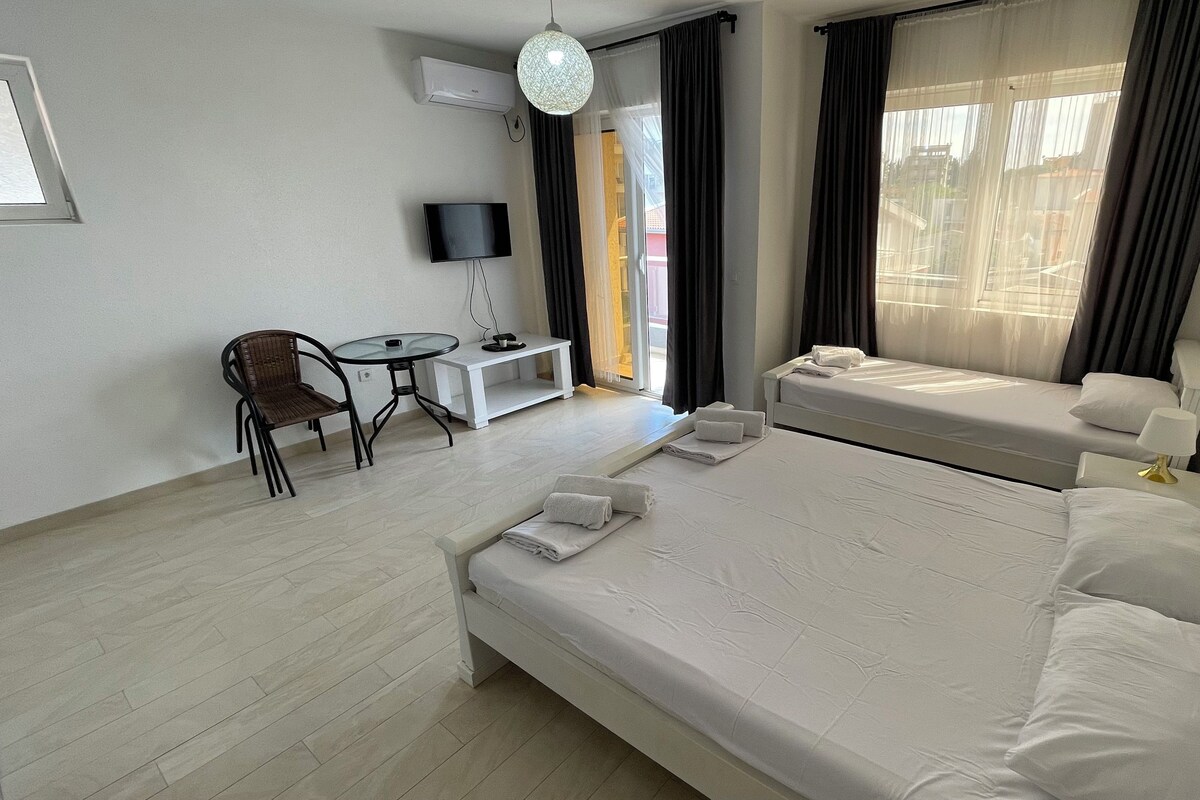 A hotel room with a large bed, a desk with a chair, a TV, and a window with curtains.