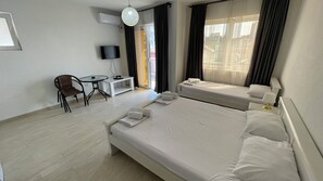 A hotel room with a large bed, a desk with a chair, a TV, and a window with curtains. - Elma Hotel (Bar)