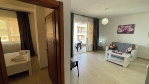 A living room with a sofa, a coffee table, and a dining area with a table and chairs. - Elma Hotel (Bar)