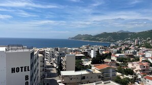 Um hotel com vários andares, varandas e vista para o mar e montanhas.