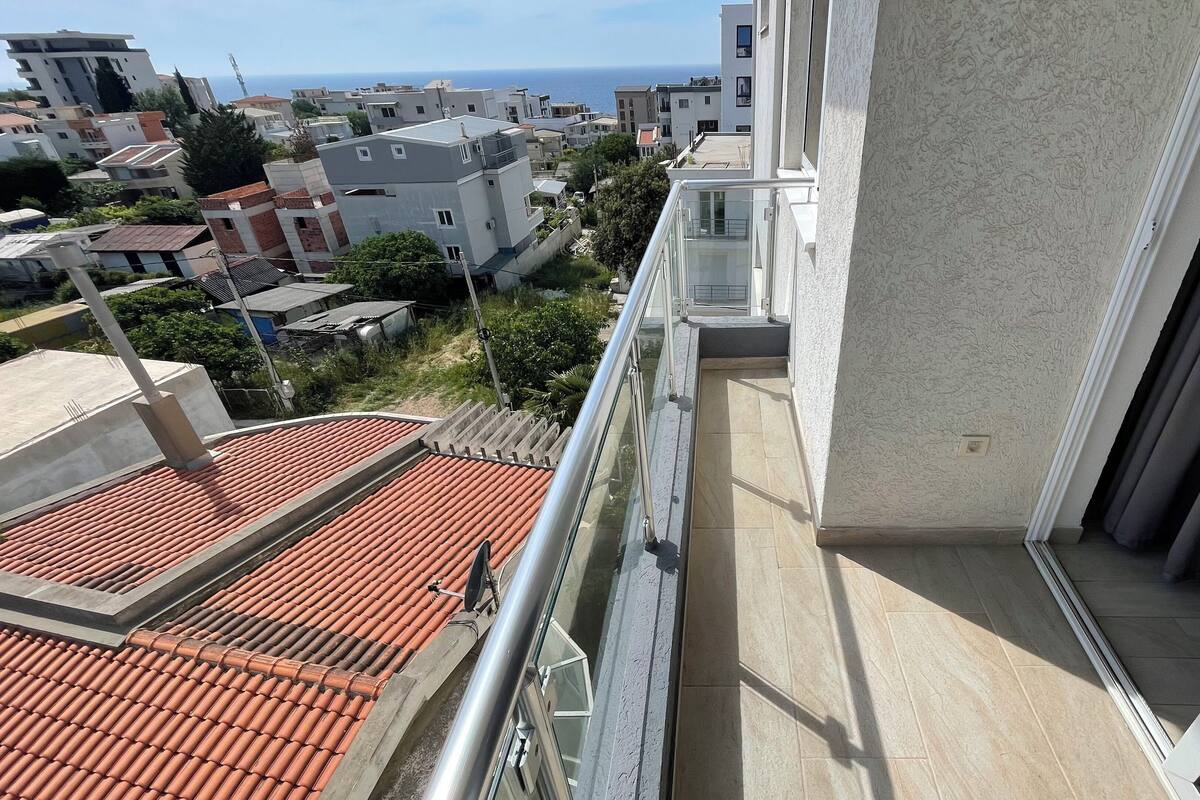 A balcony with a view of the sea and neighboring buildings.