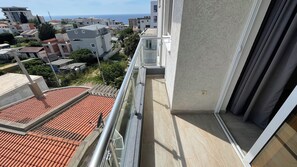 Un balcón con vistas al mar y edificios cercanos.