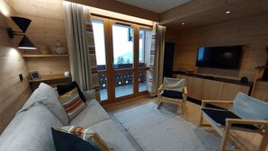 A cozy living room with a sofa, armchairs, a flat-screen TV, and a sliding glass door leading to a balcony. - 100m from resort center, 2nd floor, view valley, balcony, tv, ski locker, 63m², Valmorel (Valmorel)