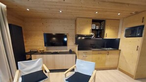 A modern kitchen with wooden cabinets, a flat-screen TV, and a dining area with two white chairs. - 100m from resort center, 2nd floor, view valley, balcony, tv, ski locker, 63m², Valmorel (Valmorel)