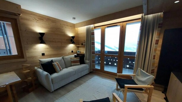 A modern living room with a sofa, chairs, a small table, and a large window with a view. - 100m from resort center, 2nd floor, view valley, balcony, tv, ski locker, 63m², Valmorel (Valmorel)