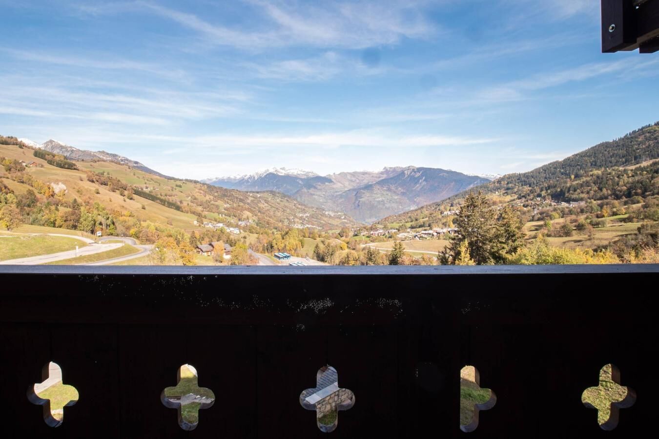 A scenic view from a balcony overlooking a valley with mountains in the distance.