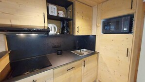 A compact kitchen with wooden cabinets, a black countertop, a built-in microwave, and a coffee maker. - 100m from resort center, 2nd floor, view valley, balcony, tv, ski locker, 63m², Valmorel (Valmorel)