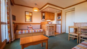 A cozy room with a wooden bench, a sofa, a small table, and a kitchenette with wooden cabinets and a microwave. - 100m from resort center, 2nd floor, view valley, balcony, tv, ski locker, 63m², Valmorel (Valmorel)