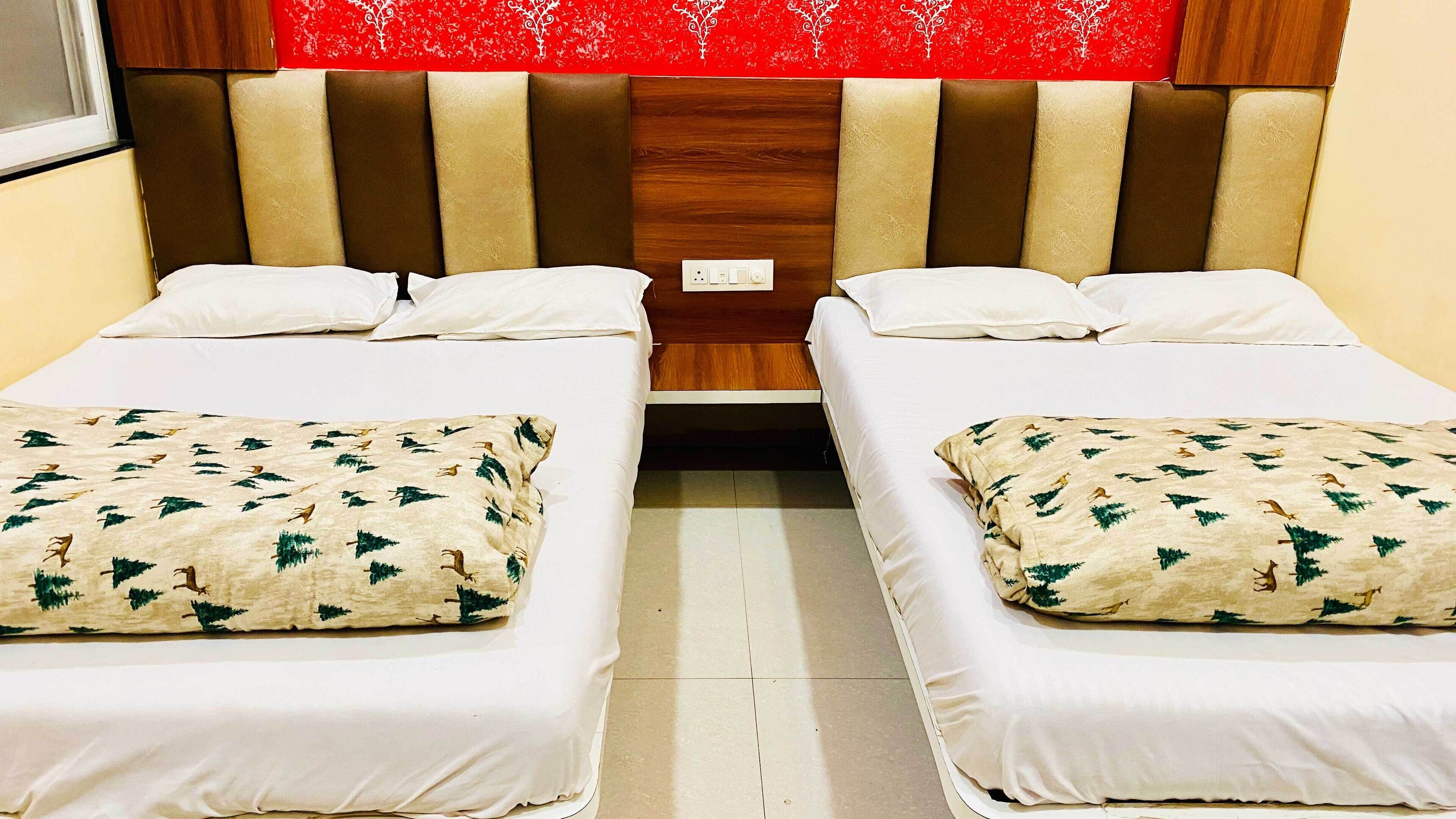 Cama doble con cabecera roja y colcha blanca estampada con motivos forestales.