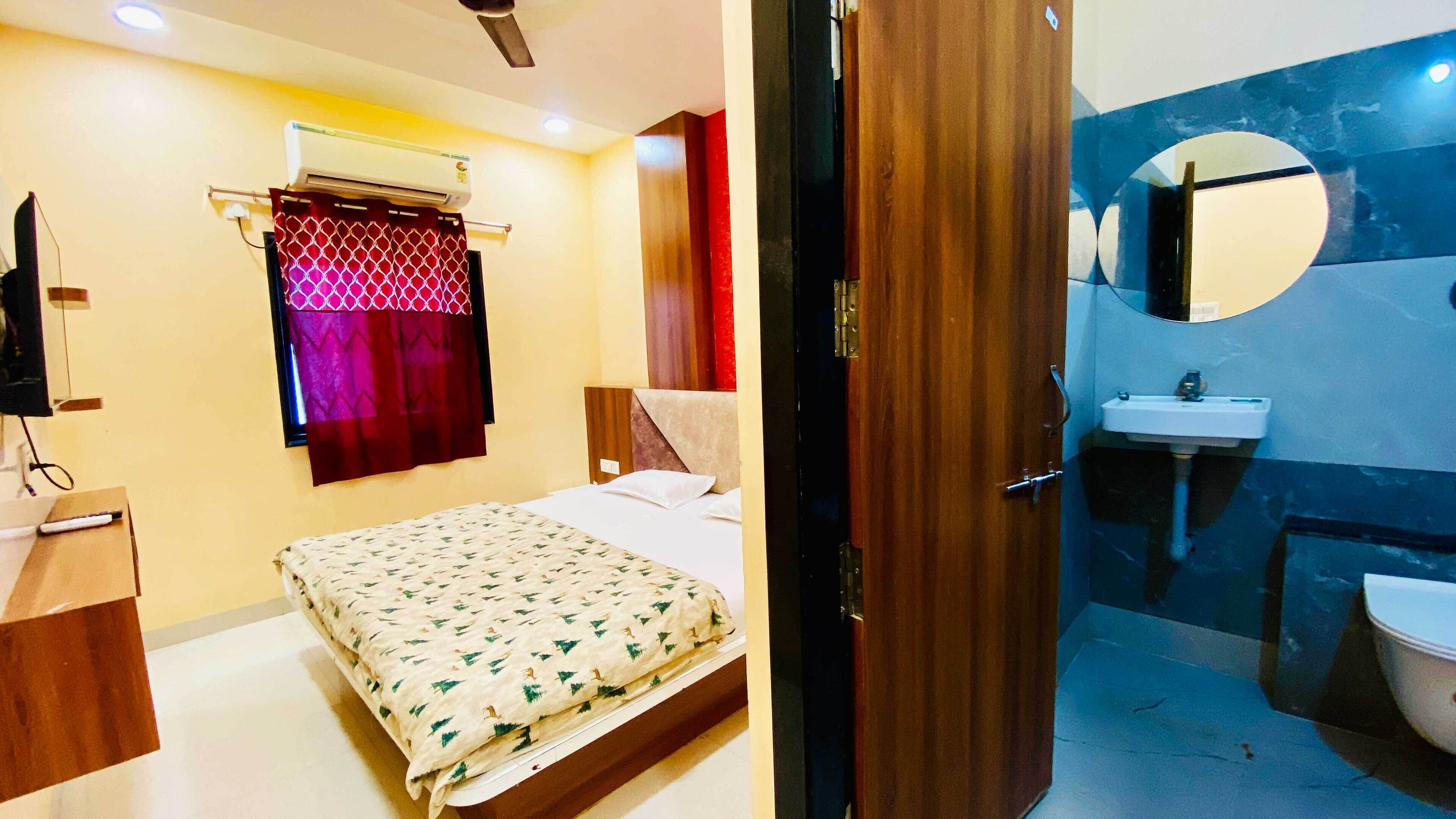 A bedroom with a bed, an air conditioner, a TV, and a window with curtains.