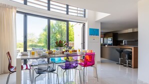 Een moderne keuken met een groot raam, een eethoek met kleurrijke stoelen, en een bar.