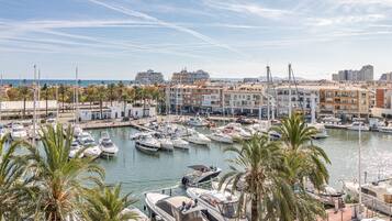 Un puerto deportivo con numerosas embarcaciones amarradas, rodeado de edificios y palmeras.