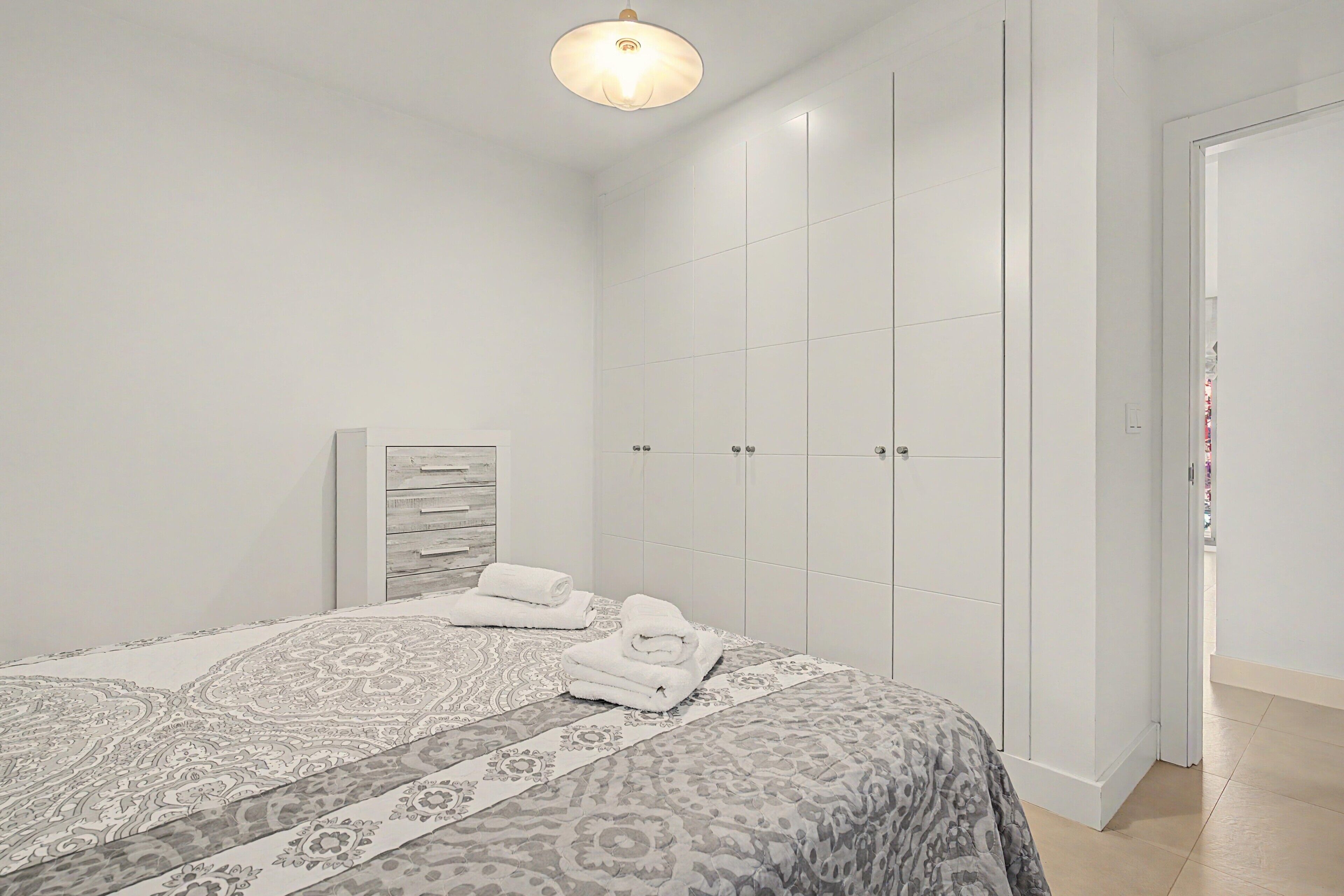 Een slaapkamer met een bed, een kledingkast en een deur.