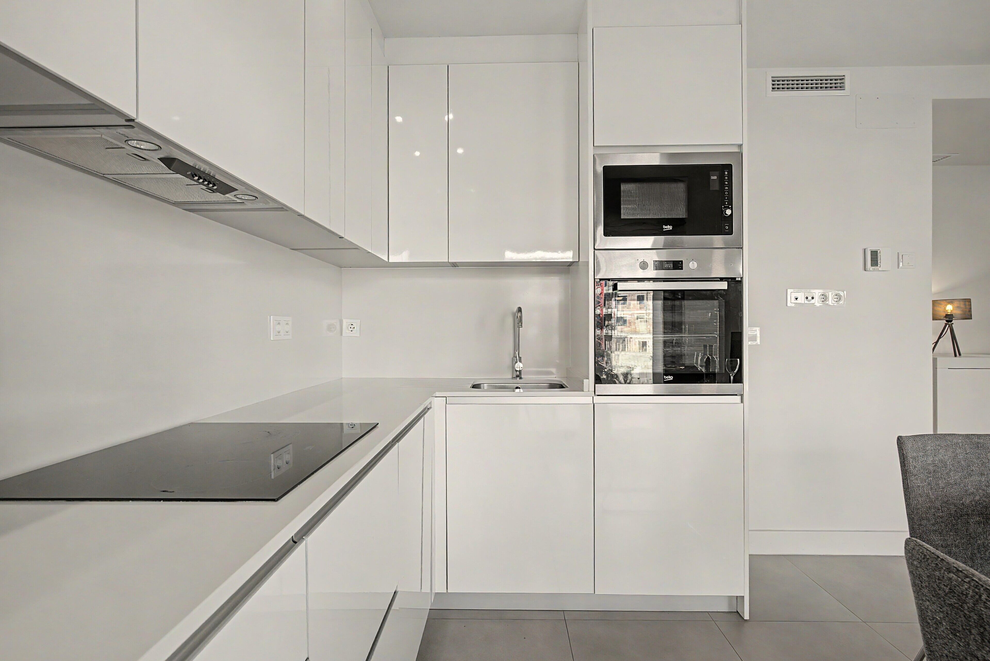 Una cocina moderna con armarios blancos, microondas integrado y horno.