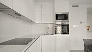 Una cucina moderna con mobili bianchi, un forno a microonde integrato e un forno.