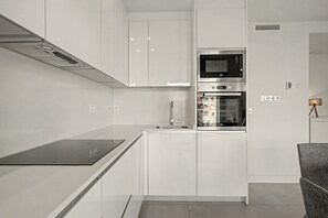 A modern kitchen with white cabinetry, a built-in microwave, and an oven.