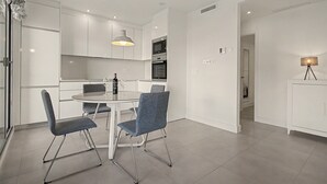 Una cucina moderna con mobili bianchi, un tavolo da pranzo con sedie e una lampada a sospensione.