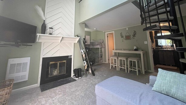 Un vaste espace de vie comprenant une cheminée, une table à manger et un escalier menant à l’étage supérieur.