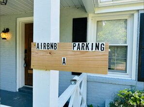 Un letrero de madera que dice 'AIRBNB ESTACIONAMIENTO A' en un porche.