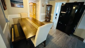 Un comedor con una mesa y sillas de madera, un refrigerador negro y un armario de madera.