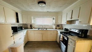 Una cocina compacta con armarios blancos, un microondas, una estufa y un lavabo.