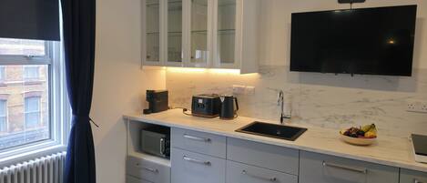 A modern kitchen with a built-in microwave, a coffee maker, a toaster, and a sink.
