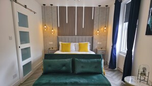 A modern bedroom with a bed, green sofa, and a round coffee table with a vase and candle.
