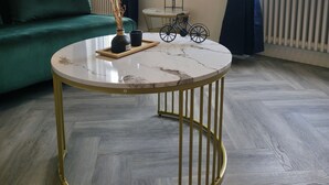 A modern living room with a round marble coffee table, a green sofa, and a bicycle decoration on a small table.
