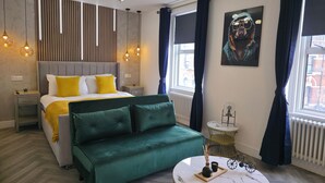 A modern bedroom with a bed, green sofa, and a round table with a vase.