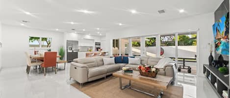 A modern living room with a sofa, coffee table, and dining area.