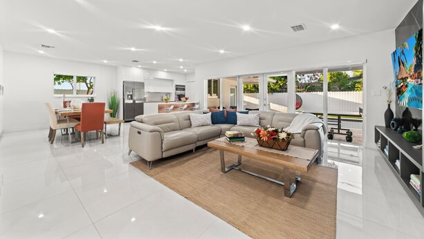 A spacious living room with a large sofa, a coffee table, and a dining area with chairs and a table. - Family Retreat: Pool, Games & Private Apartment (Miami)