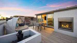 A modern outdoor patio with a fire pit, seating area, and a dining table. - 200 East Balboa Oceanview Rooftop Steps to Sand, Pier, Boardwalk & Dining (Newport Beach)