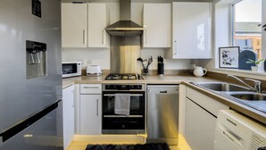 Een moderne keuken met roestvrijstalen apparatuur, witte kasten en een inbouwfornuis.