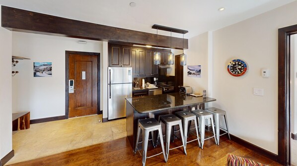 A modern kitchen with a central island, stainless steel appliances, and bar stools.
