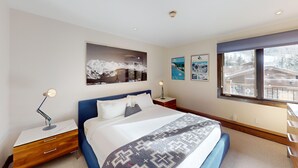 Quarto com cama, mesas de cabeceira, janela com vista e decoração nas paredes.