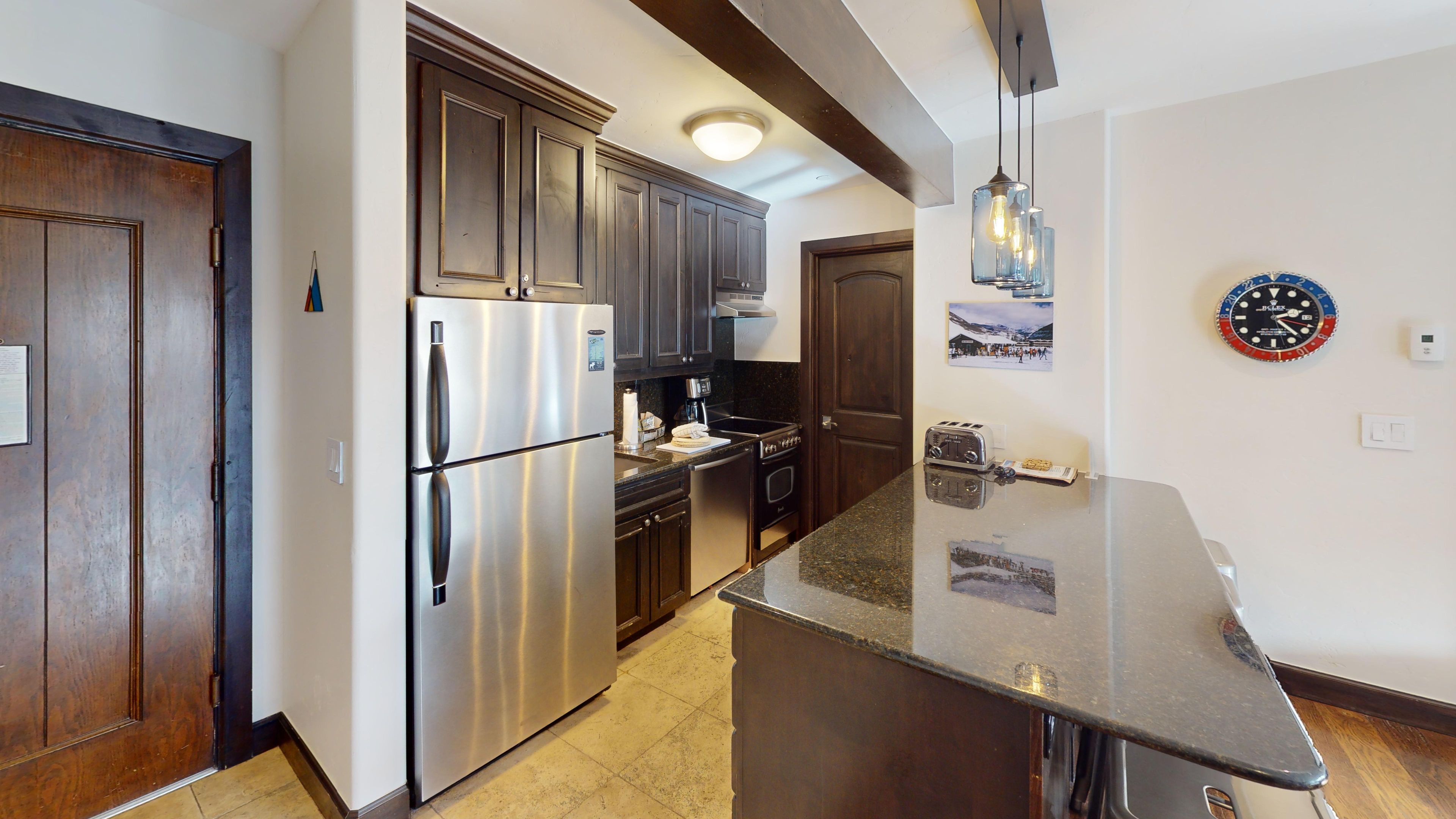 A modern kitchen with stainless steel appliances, dark wood cabinets, and a central island.