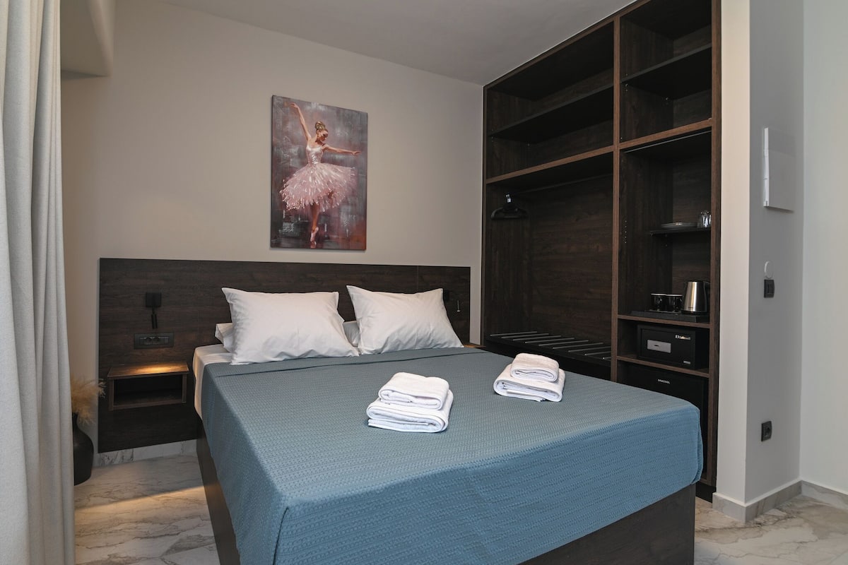 A bedroom with a large bed, a nightstand, a wall-mounted shelf, and a wardrobe.